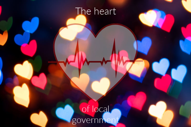 A heart shape with an EKG line over a heart bokeh background with the words "The Heart of local government"