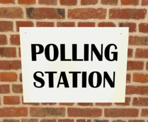 Sign reading "polling station" on a brick wall