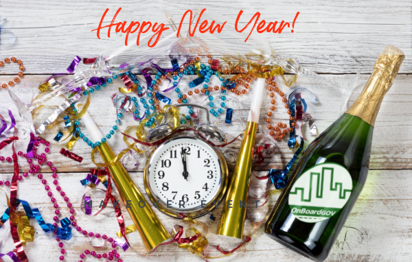 Flat lay of clock, horns, wine bottle and streamers with "Happy New Year!" above.
