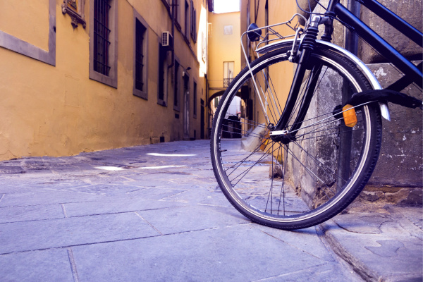 A bicycle leans against the wall of a building in a clean alleyway.
